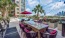 a patio with chairs and tables and umbrellas and buildings in the background